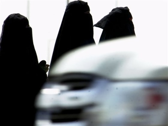 Saudi women walk past cars in a Riyadh, Saudi Arabia, street.